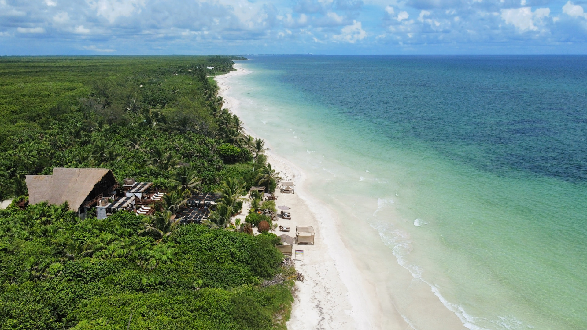 Aerial view of Hayhu Beach Club, its long white beach and turquoise Caribbean water